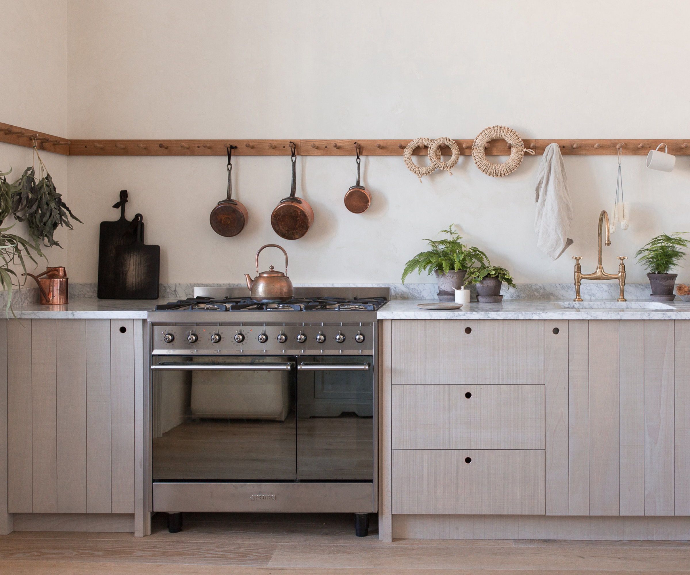 pale kitchen units with shaker peg rail running around back and side wall