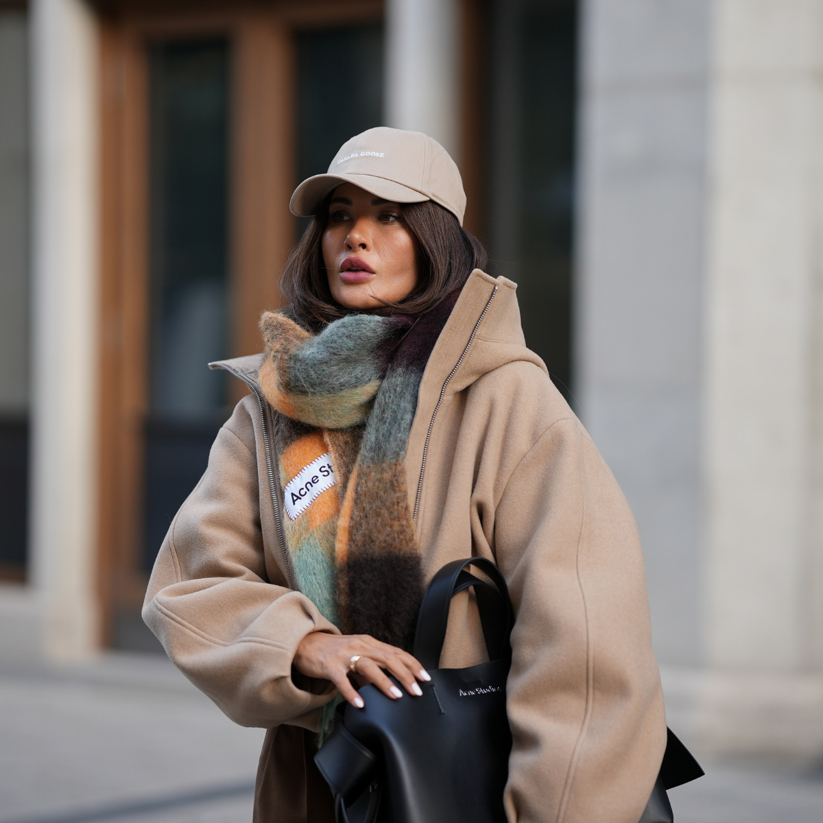cold weather skincare Füsun Lindner is seen wearing a beige baseball cap with minimal branding from Canada Goose; an oversized checked scarf in muted earthy tones, with a soft and fluffy texture from Acne; 