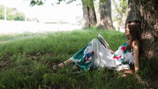 Woman sitting under a tree reading a book