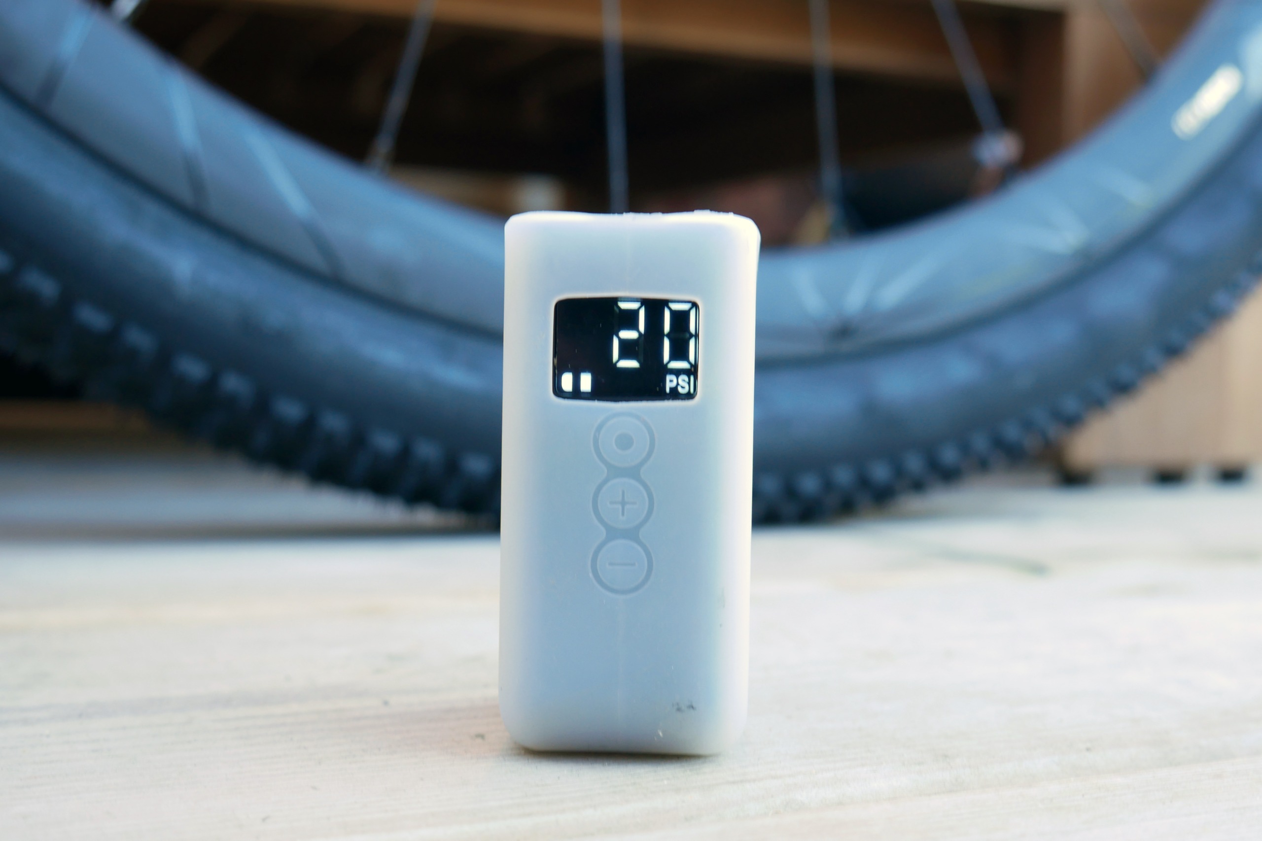 A Cycplus AS2 Ultra electric pump placed on a wooden deck, displaying 20PSI with a gravel tyre in the background