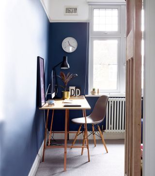 office space with blue walls and slim wooden desk, gray desk chair and grey carpet