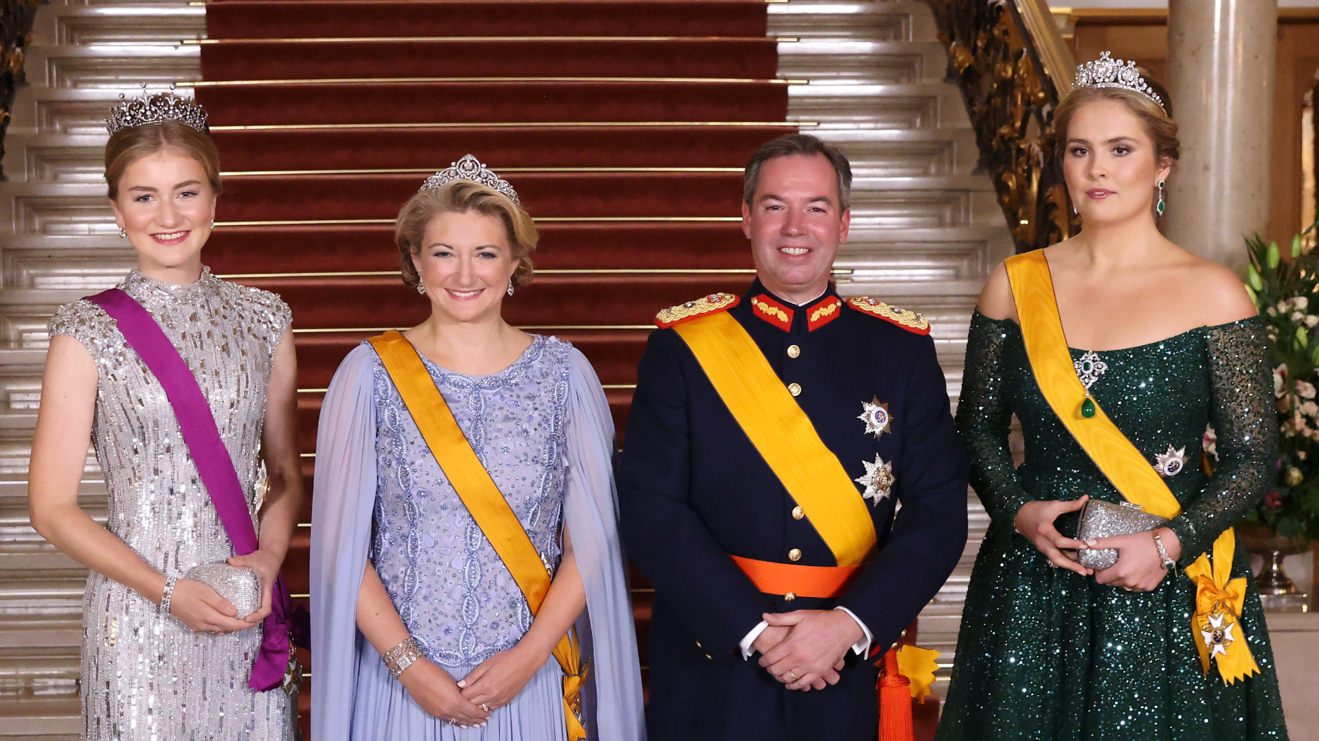 Princess Elisabeth, Grand Duchess Stephanie, Grand Duke Guillaume, Princess Catharina-Amalia wearing evening gowns and military uniform in front of a staircase
