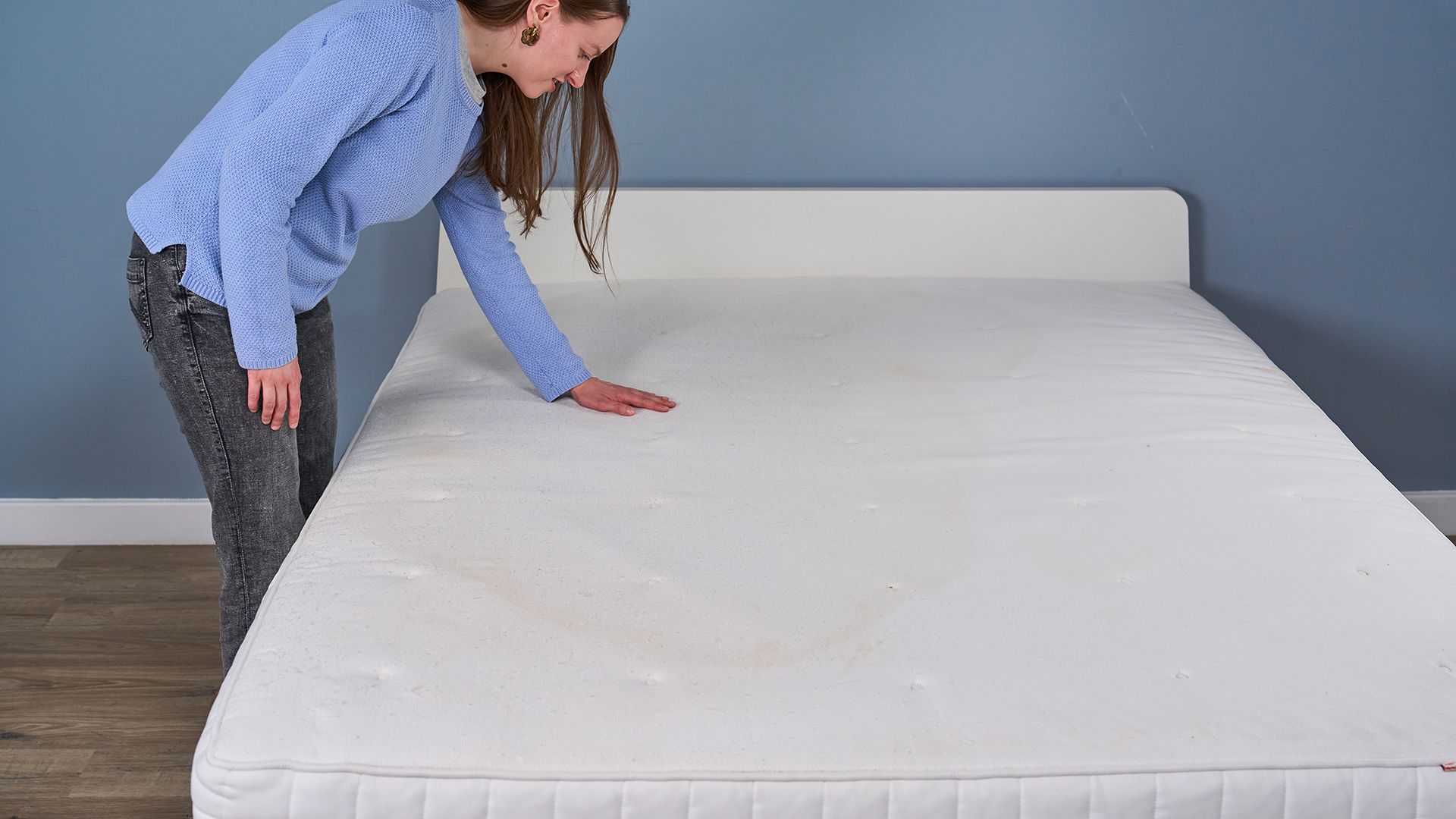 Frances Daniels inspects the surface of a dirty mattress, which has a yellow sweat stain