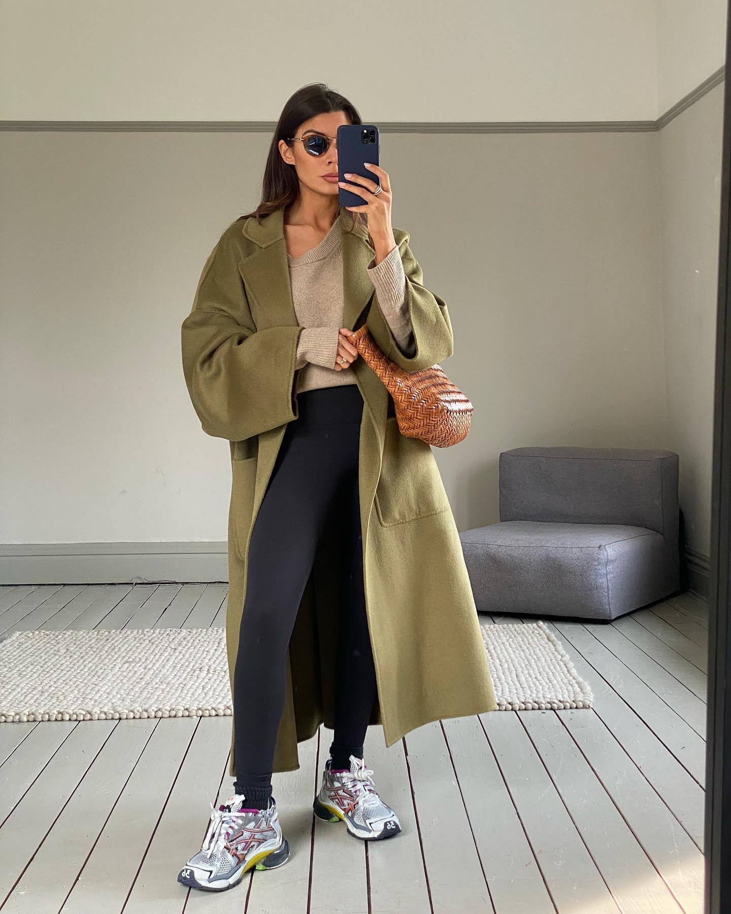 @smythsisters wears full length black leggings with a trench coat and a woven basket bag.