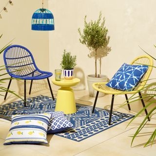 Blue and yellow string back outdoor chairs with side table and patterned rugs and cushions