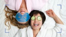 Two women laughing on a bed while enjoying skincare for makeup face masks