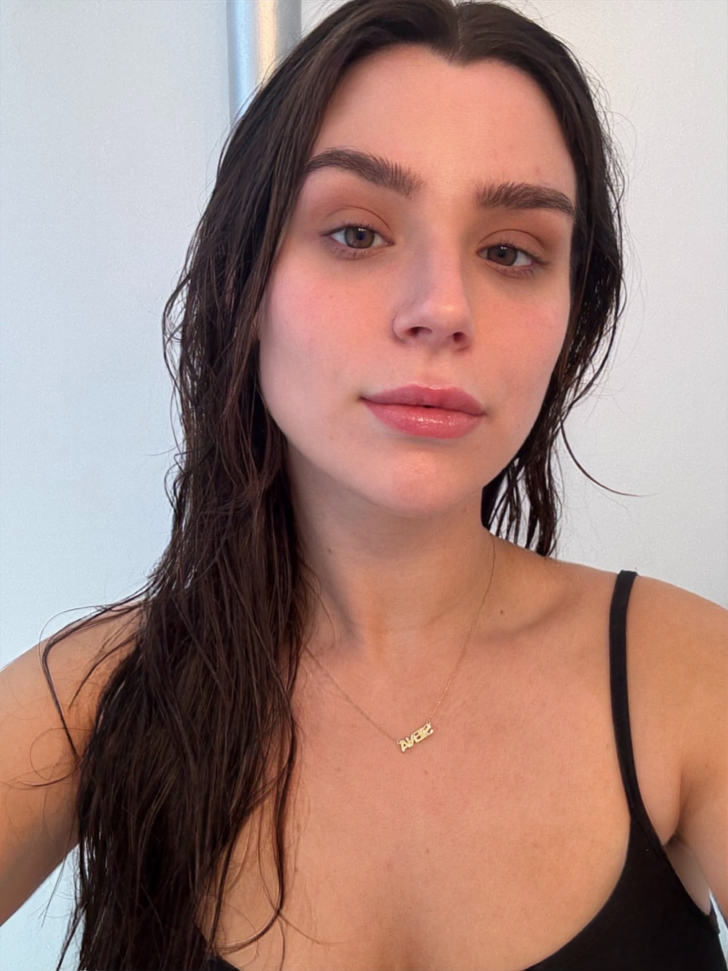 a girl in a black tank top and brown hair after applying spf.