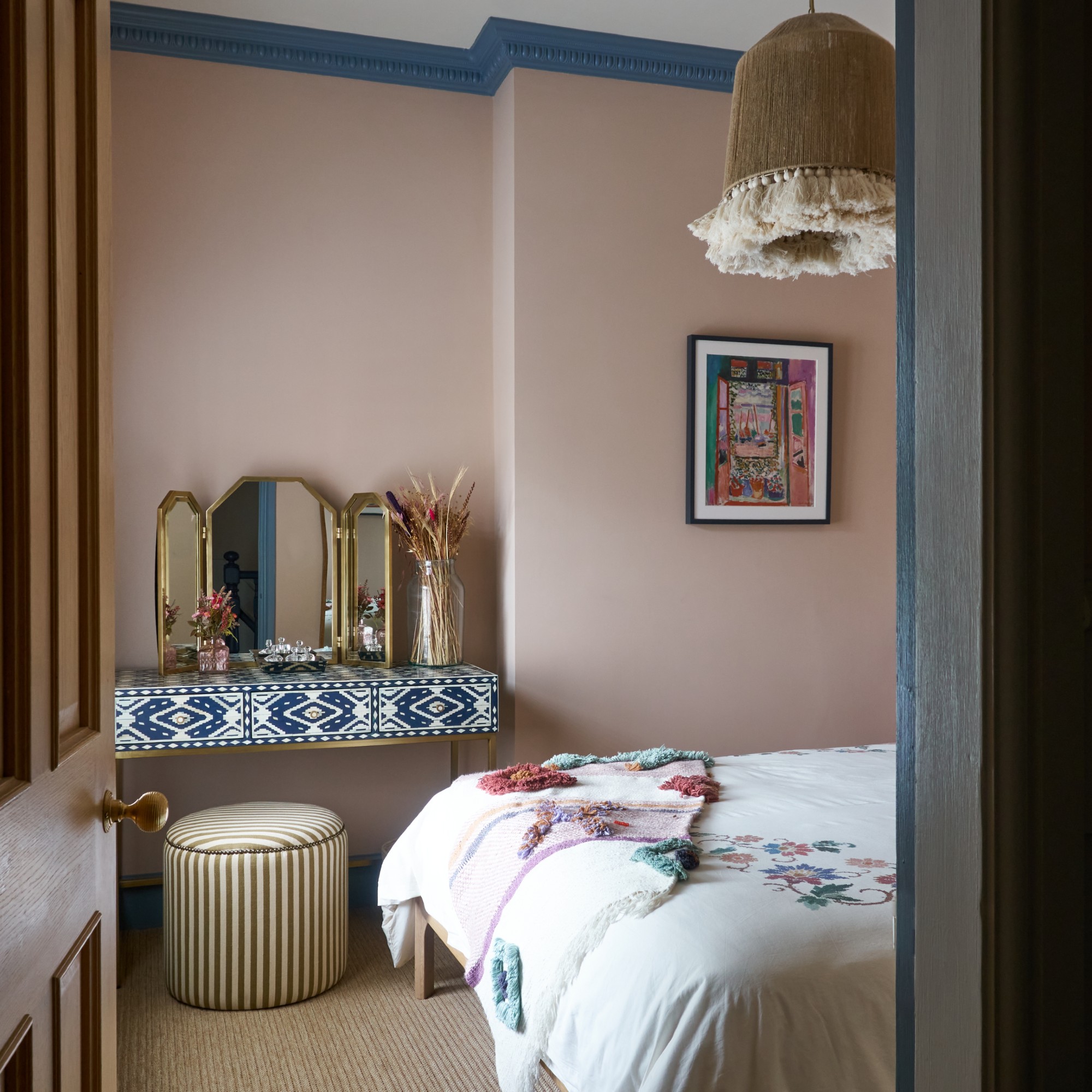 A bedroom painted in a soft pink shade with dark blue trims and skiting boards