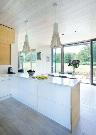 white lacquered kitchen units in an open plan kitchen diner and living space