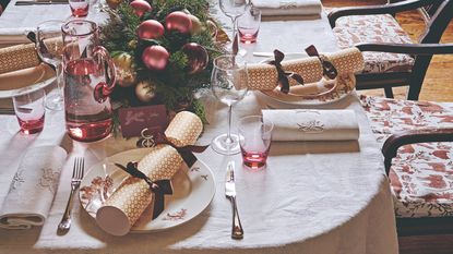 A Christmas table setting with a scalloped placemat and napkin and ribbon-decorated cracker