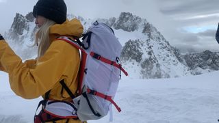 Hiker wearing a white backpack on a glacier