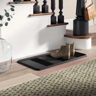 A boot tray in an entryway by stairwell