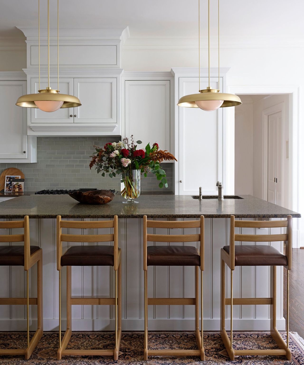 A white kitchen with an island and wooden stools