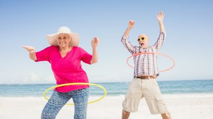 An older couple plays with hula hoops on the beach to celebrate using DAFs to maximize charitable giving.
