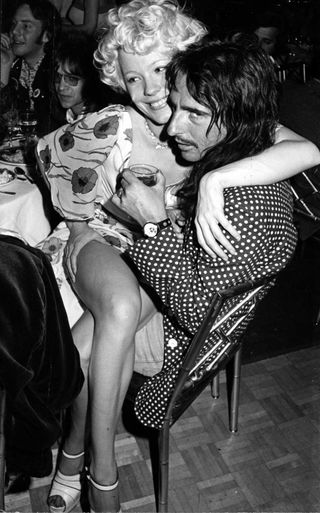 Pamela De Barres sitting on Alice Cooper's lap at a party