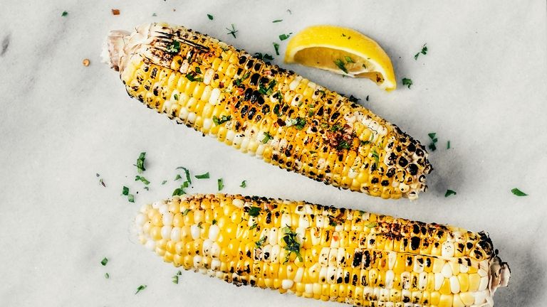 Grilled corn with spices and herbs on white background