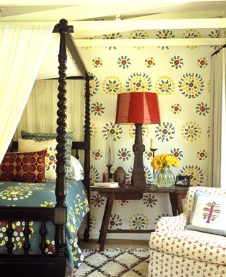 patterned wallpaper in a bedroom with a four poster bed