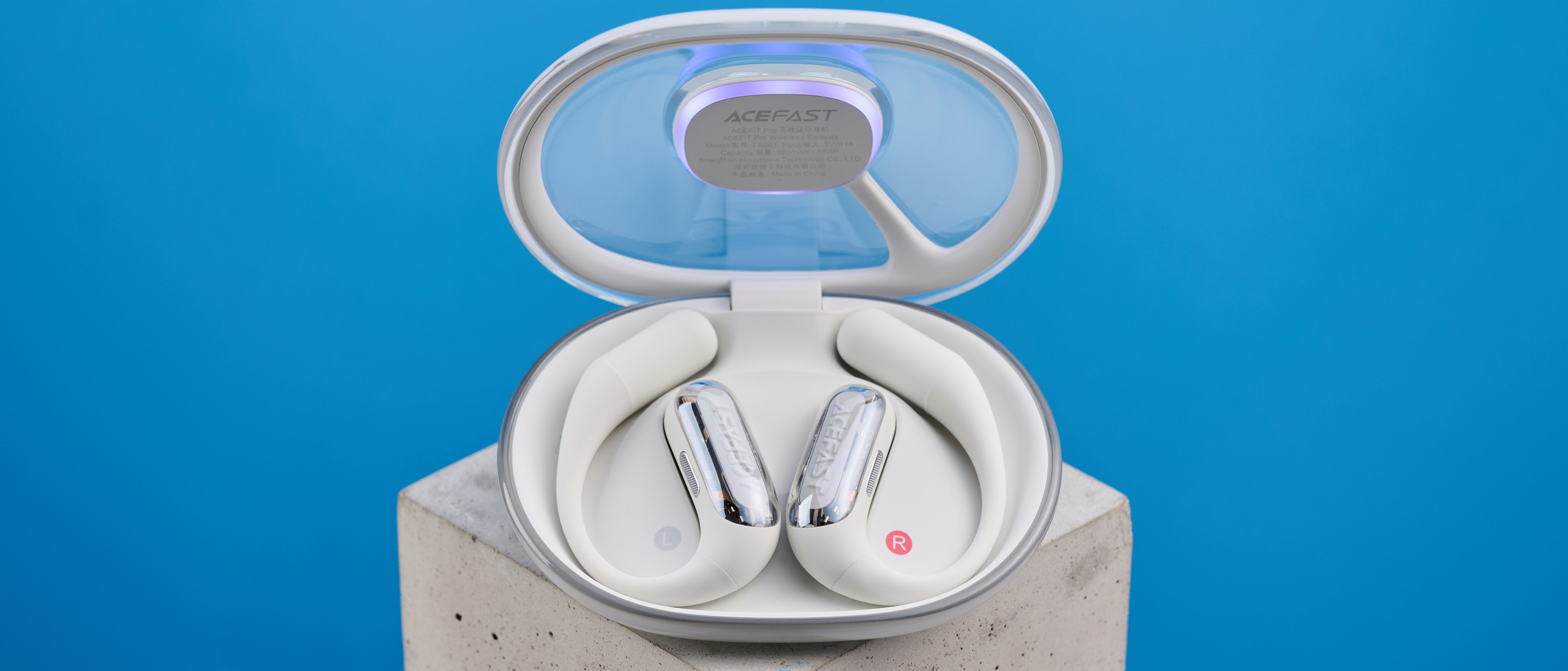 AceFast AceFit Pro open earbuds and the light up charging case photographed in front of a blue background.