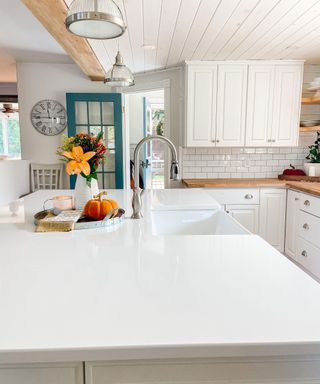 White kitchen counters with silver detail and glass pendant lighting