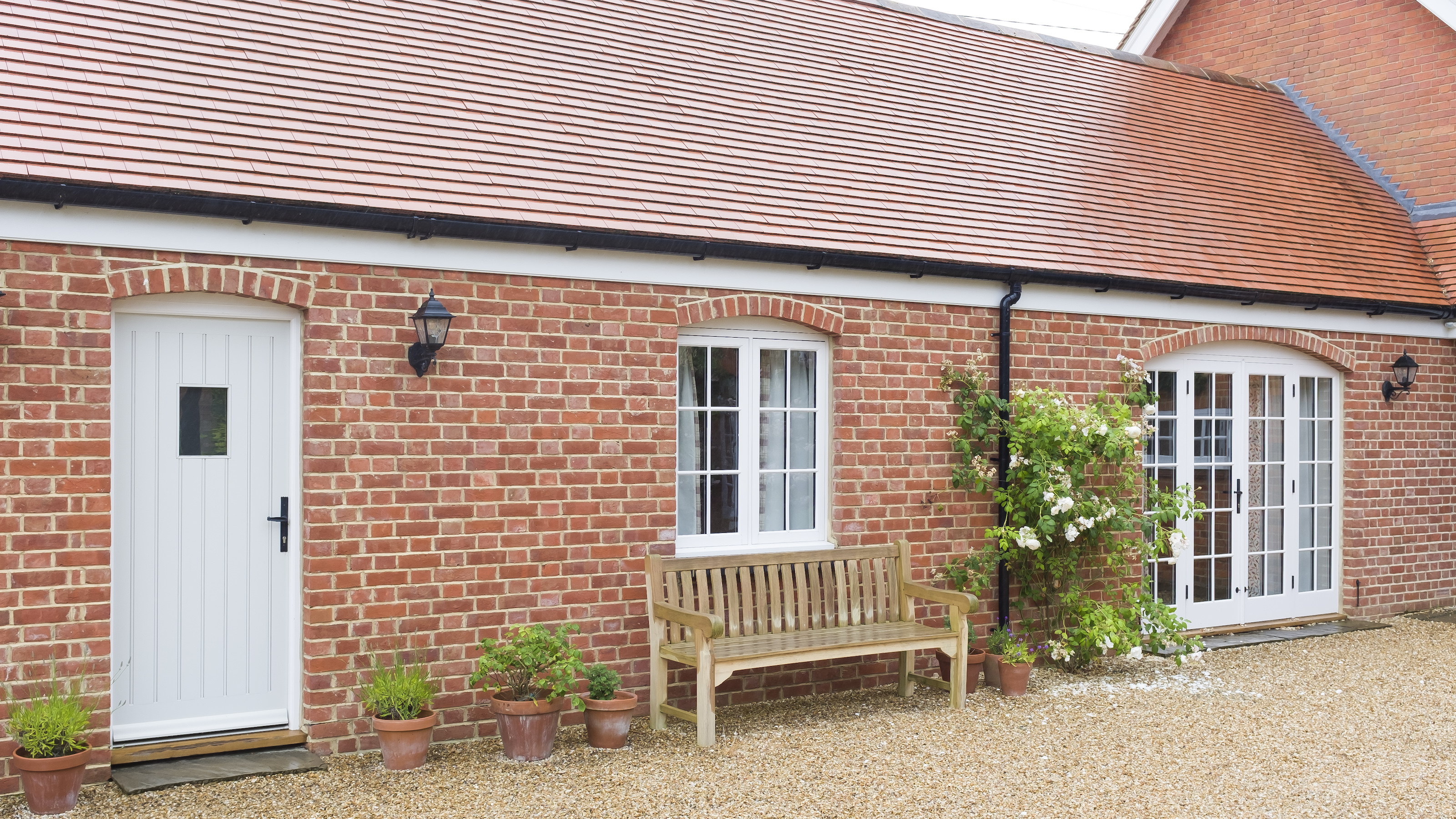 House extension providing a single storey annexe with side of house just showing and gravel driveway in front