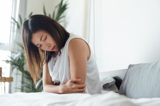 Living with chronic pain: Young Woman Suffering Stomach In Bed