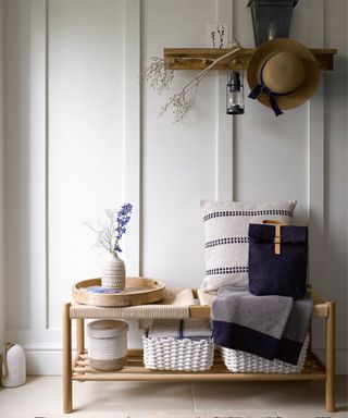An entryway with a wooden bench with pillows and decor on it