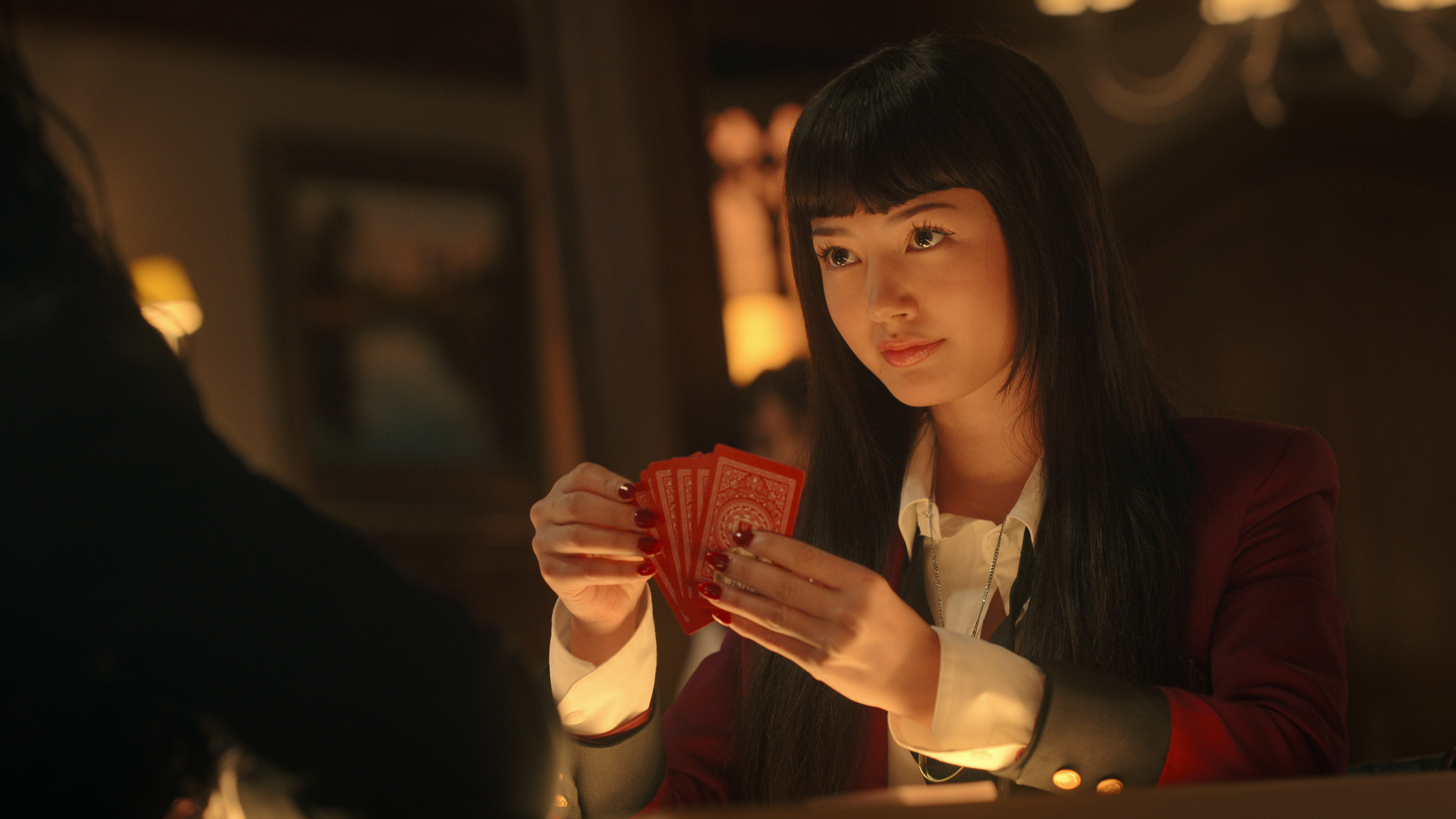 Yumeko (Miku Martineau) with cards in hand in a scene from Netflix's "Kakegurui" adaptation, "Bet"
