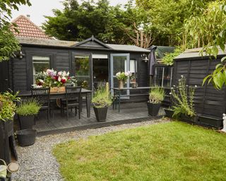 A professional florist studio painted black at the bottom of a lawned garden