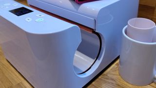 HTVRONT auto tumbler heat press review; a large white craft machine on a table with a cylindrical gap