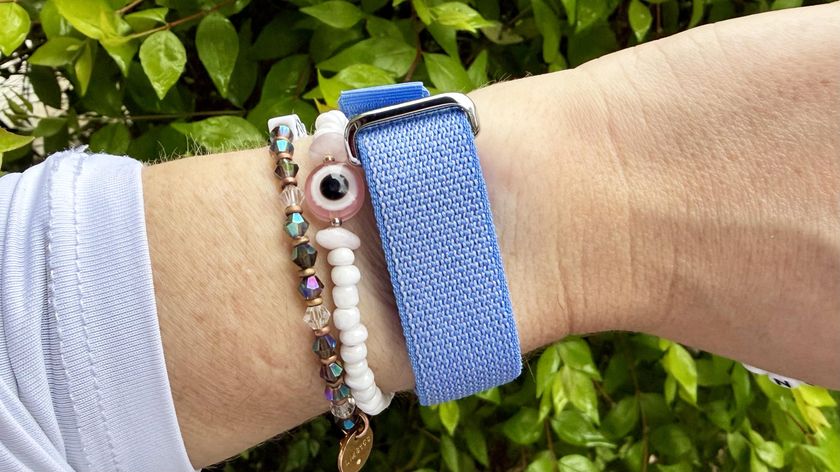 Person wearing the Fitbit Air on their wrist with a blue strap alongside other bracelets 