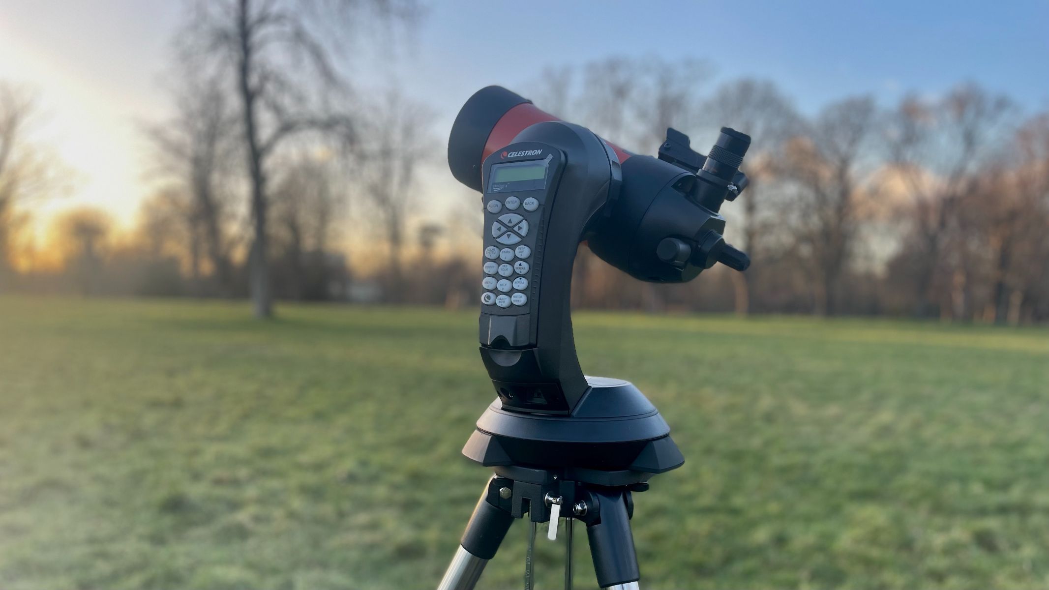 The celestron nexstar 4se set up outside in a field facing away from the camera