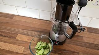 Nutribullet Magic Bullet Kitchen Express on a kitchen countertop next to a bowl of cucumber which has been sliced using the food processor attachement