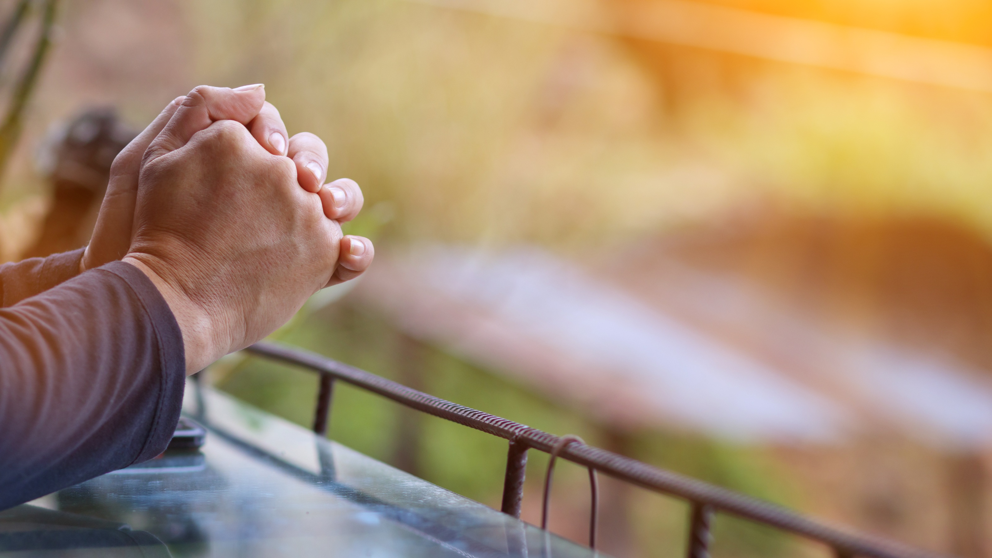 A man prays, only his folded hands showing.