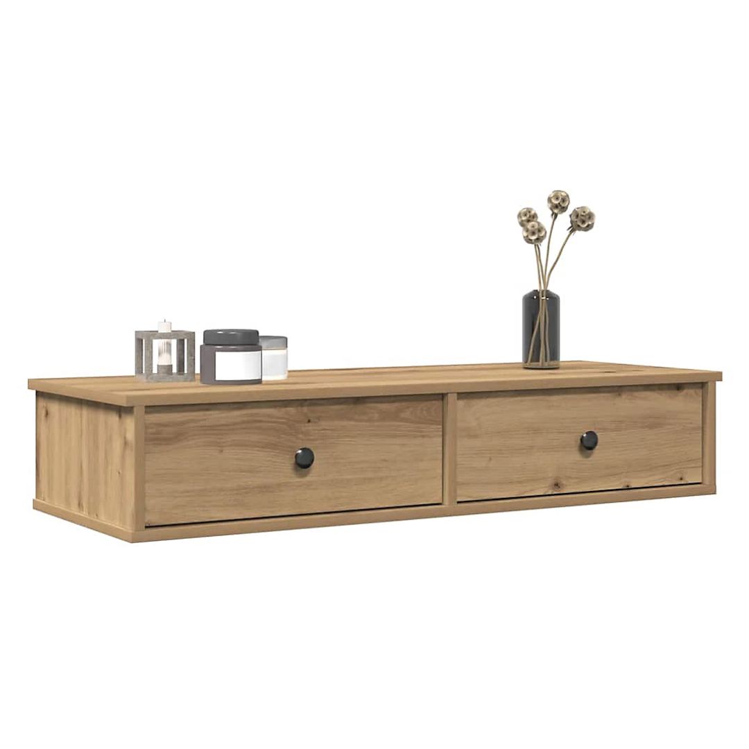 A low, rectangular wall shelf made from light oak wood with visible grain. It features two wide drawers with small round black knobs. On top sit a lantern-style candle holder, two small jars, and a dark vase holding delicate dried stems.