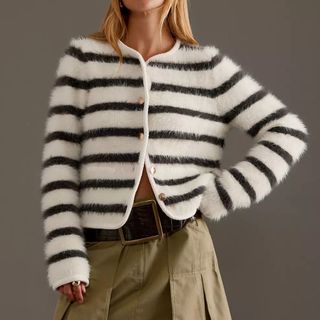 A model wearing a black and white fluffy stripy cardigan with a khaki skirt