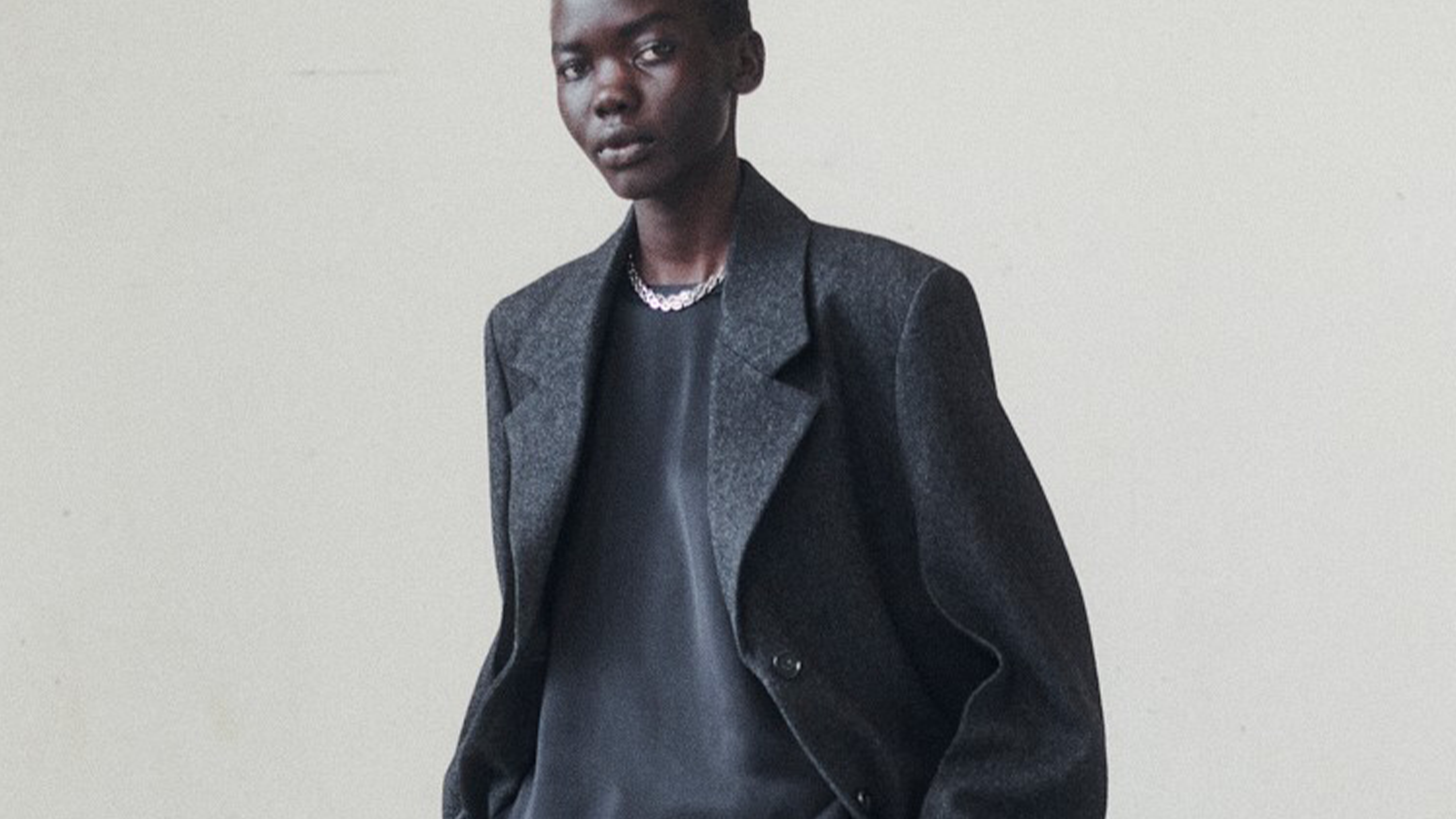 Toteme model wearing black leather jacket, black sweater, and black pants.