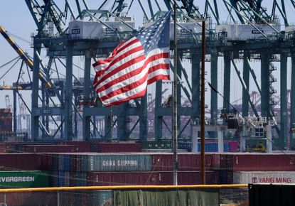 A U.S. flag with Chinese shipping containers in the backdrop