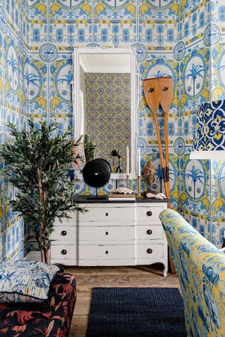 Dresser against the wall in a blue and white room with maximalist wallpaper