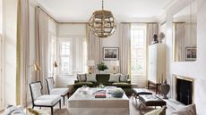 Modern beige and white living room with hints of gold and green, including beige and gold curtains, a gold lampshade and green sofa
