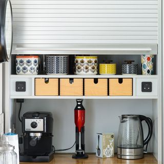 Tambour unit in a grey kitchen used to hide away a tea and coffee station