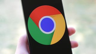 Google Chrome logo on an Android phone held in one hand.