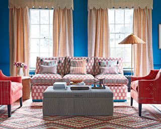 A living room curtain idea with blue walls, red and white sofa, and cream curtains with pelmet