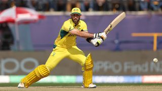 Glenn Maxwell of Australia, wearing bright yellow kit, swings his bat at the crease ahead of the India vs Australia live stream for the Cricket World Cup final 2023.