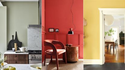 A green kitchen with a block chopping board leaning against the wall / red wall paint with a black chair in a corner / A white doorframe into a dining room on a yellow wall
