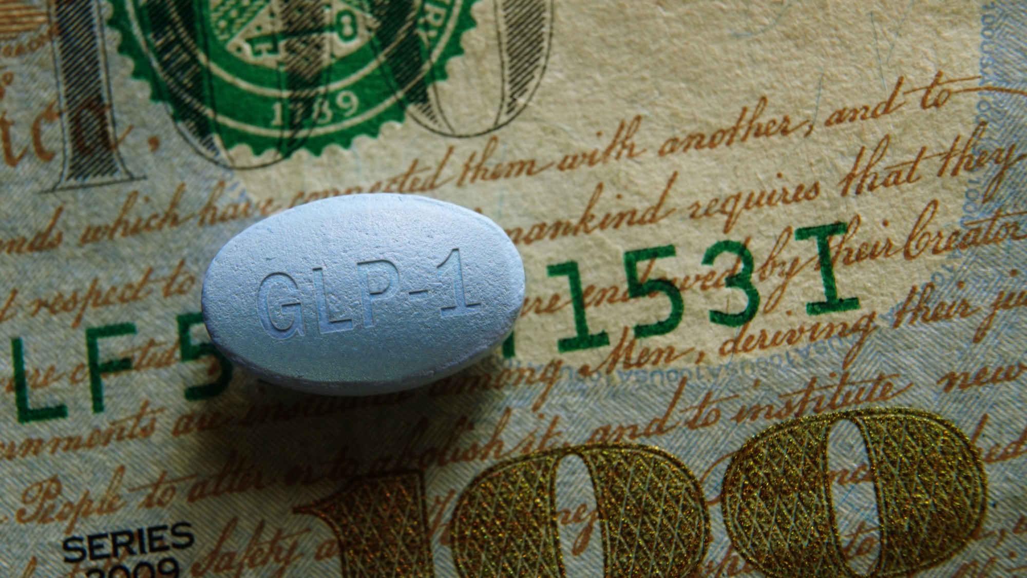Closeup of a GLP-1 pill on a US hundred dollar bill