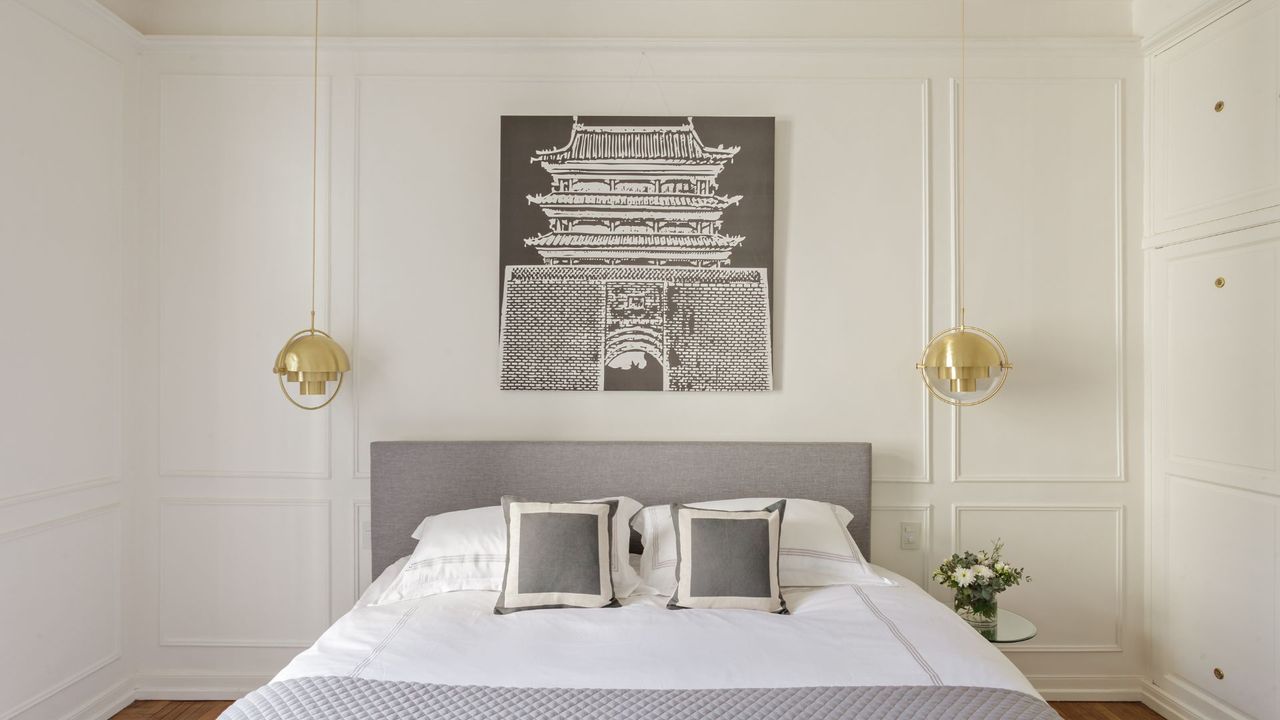 A bedroom with clear white wall paneling and gold lighting features