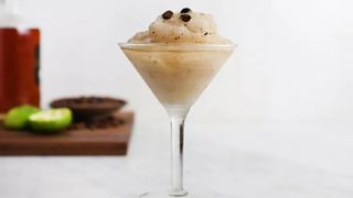 martini glass loaded with a beige blended daiquiri and topped with three coffee beans