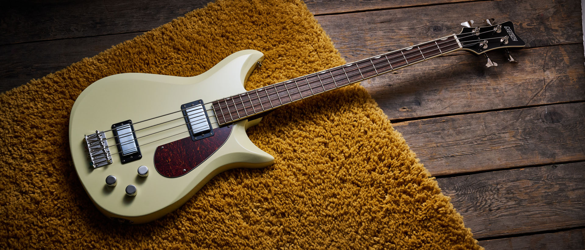 Gretsch Electromatic CVT Bass Double-cut: the retro-styled cream-colored four-string is pictured in close-up against a shaggy brown carpet.