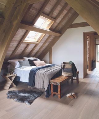 Barn extension decorated with a stylish Scandi feel. Bedroom in attic with wooden walls and double bed.