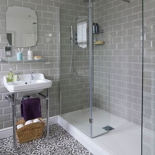 bathroom with grey brick wall wash basin shower cabin and white and black designed flooring